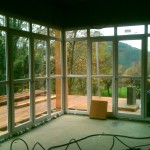 Le vitrage du salon, angle sud-est, est posé. Chaque baie vitrée offre une ouverture sur la terrasse. La qualité du paysage est valorisée grâce à un angle de vue possible de 90°.